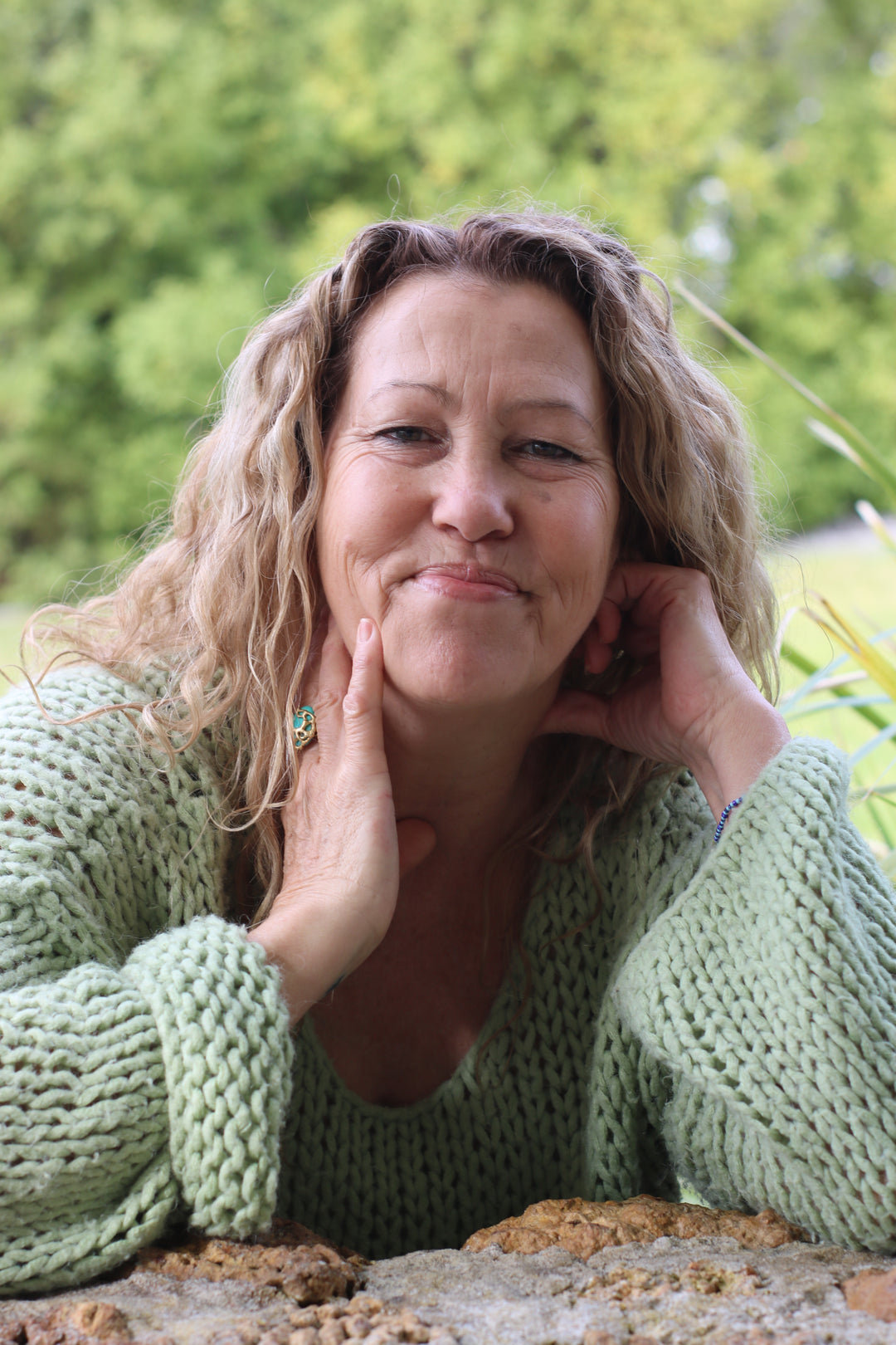 Photo of Julie with her hands on her face wearing a green sweater smiling