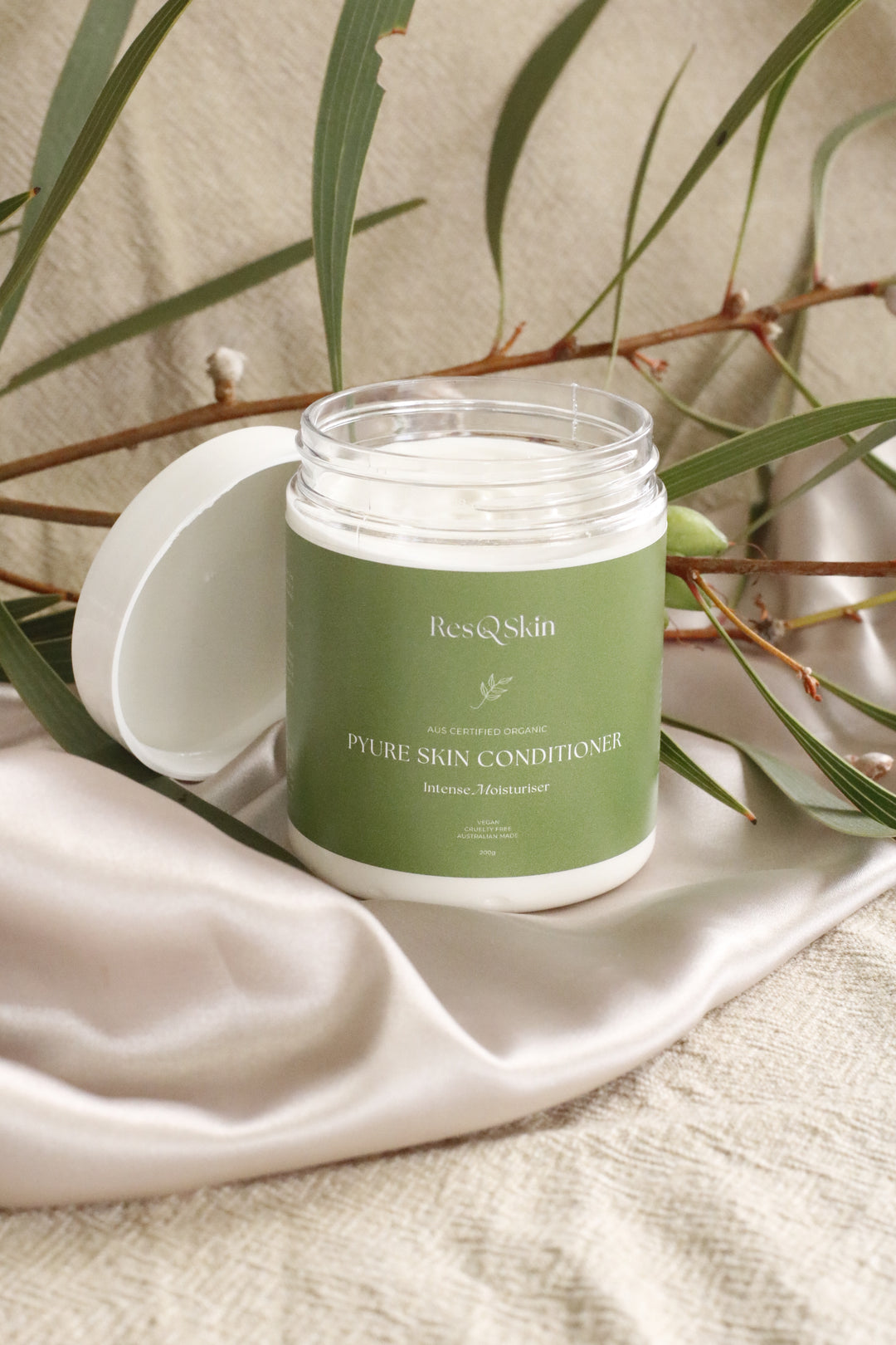 Photo of Pyure Skin Conditioner standing on a smooth fabric with leaves on the background